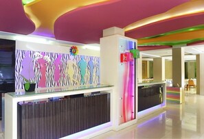 Welcome to our reception area, featuring a unique wavy ceiling, colorful abstract art, and a stylish seating area.