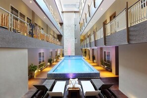 Relax by the central pool surrounded by lounge chairs and a seating area.