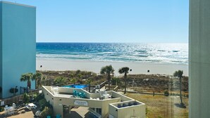 A hotel with a pool area, beach view, and outdoor seating.