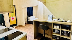A compact hotel room with a kitchenette, a bed, a desk, and a small seating area. - SA Studio 24 (Tirana)