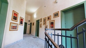 A hallway with framed pictures on the walls, a green door, and a wooden handrail. - SA Studio 24 (Tirana)