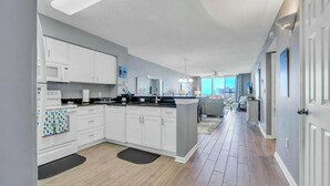 Une cuisine moderne avec des meubles blancs, un plan de travail noir et un plancher en bois.