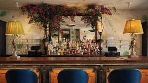 A bar area with a wooden counter, multiple liquor bottles, and two lamps. - Hotel Lulu (Round Top)