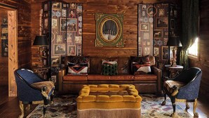 A log cabin interior with a sofa, ottoman, two armchairs, and a patterned rug. - Hotel Lulu (Round Top)