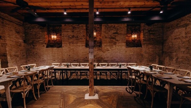 A rustic dining area with wooden tables and chairs, brick walls, and exposed beams. - Hotel Lulu (Round Top)
