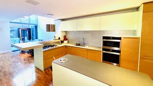 Eine moderne Küche mit Holzschränken, einer Edelstahlinsel und eingebauten Backöfen.