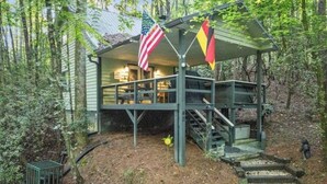 A cabin with a porch, a flag, and a flagpole.