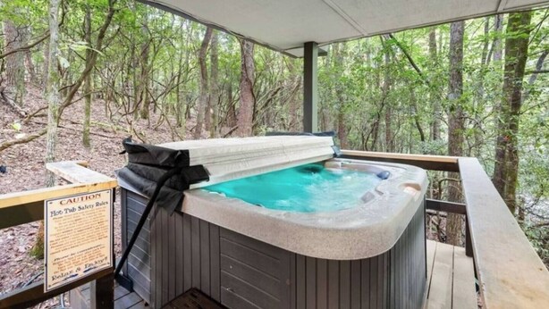 A hot tub in a forested area with a covered deck.