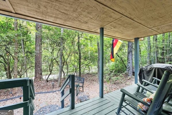 Un espacio al aire libre techado con una terraza de madera, bancos y una bandera.