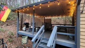 A covered outdoor deck with a barbecue grill, seating, and a welcome sign.