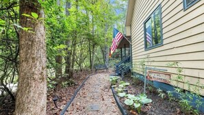 A rustic cabin with a porch, surrounded by dense forest.