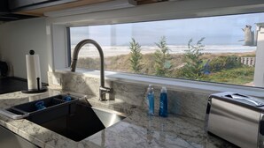 A kitchen with a sink, faucet, and a window overlooking a landscape. - Beach Therapy - on Heceta Beach (Florence)