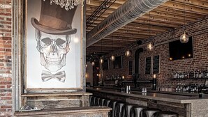 Un bar avec un comptoir en bois, des tabourets et une enseigne indiquant « TAXMAN FORTVILLE ».