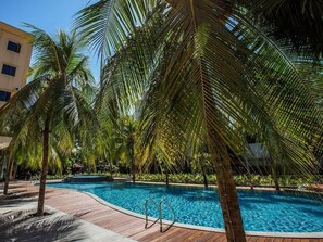 Ein Swimmingpool, umgeben von Palmen und einer Holzterrasse.