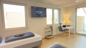 Una habitación moderna y bien iluminada con una cama, un escritorio y un televisor que muestra 'Prime Video'.