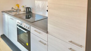 Una cocina moderna con electrodomésticos de acero inoxidable, horno empotrado y muebles de madera clara.