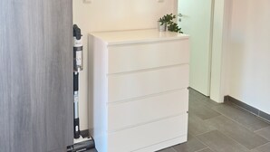 Un pasillo con un aparador blanco, un cuadro en la pared y una puerta que da a otra habitación.