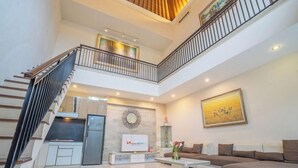 A spacious living area with a kitchen, a staircase, and a balcony.