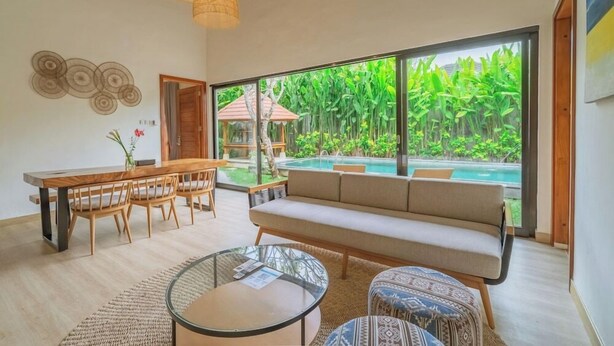 A modern living room with a large window, a pool, and a dining area.