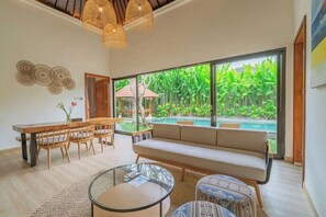 Ein modernes Wohnzimmer mit großem Fenster, Pool und Essbereich.