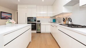 A modern kitchen with white cabinetry, a built-in oven, a microwave, and a gas stove.