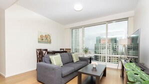 A modern living room with a grey sofa, a coffee table, and a dining area with wooden chairs.