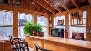 A wooden cabin interior with a bar area, chairs, a television, and various decorations. - New to VRBO Bumble Bear Inn in Bolton Landing (Bolton Landing)