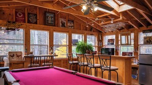 A wooden interior with a pool table, bar area, and large windows. - New to VRBO Bumble Bear Inn in Bolton Landing (Bolton Landing)