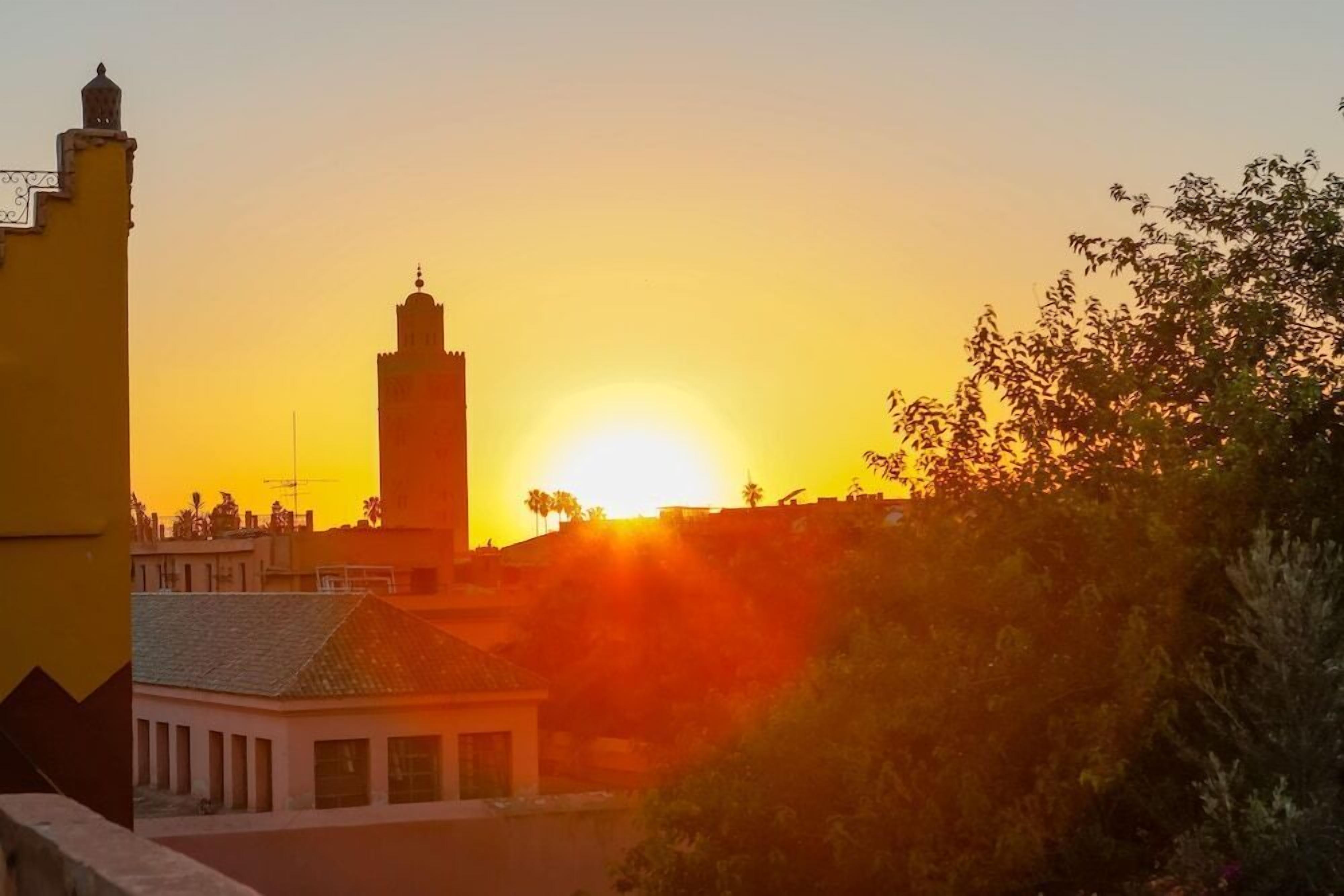 A sunset view with a prominent tower and a building with a tiled roof.