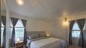 A bedroom with a bed, bedside tables, and curtains. - Quiet & Quaint 2 Bedroom 1 Bath with Yard (Fort Lee)