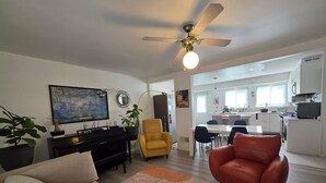 A living room with a sofa, a red armchair, a yellow armchair, a ceiling fan, and a painting on the wall. - Quiet & Quaint 2 Bedroom 1 Bath with Yard (Fort Lee)