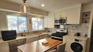 A compact kitchen with a wooden table, built-in appliances, and a washing machine. - Quiet & Quaint 2 Bedroom 1 Bath with Yard (Fort Lee)