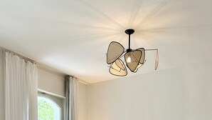 Una sala de estar moderna con un sofá, sillas, un televisor y una lámpara de techo original.