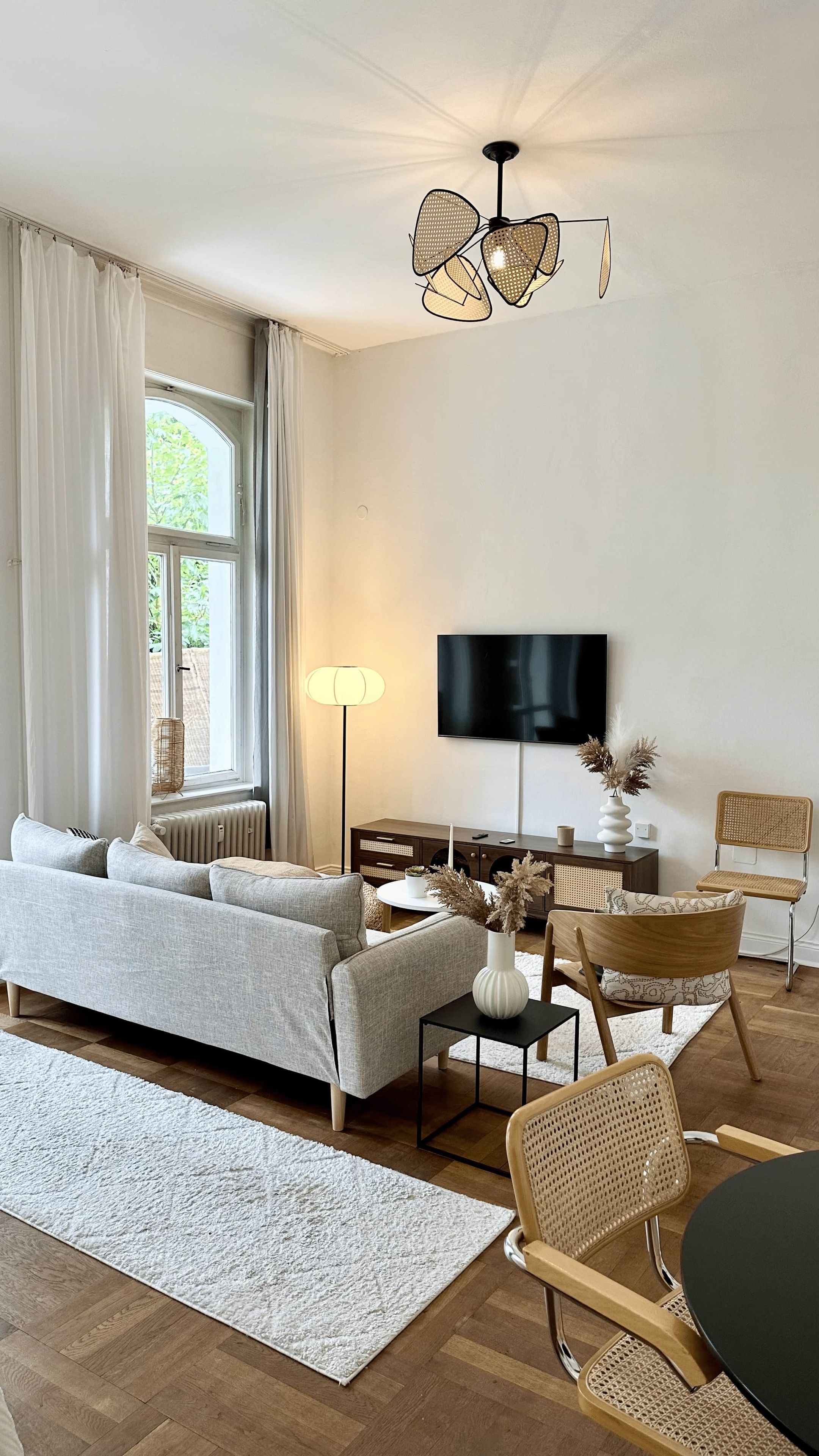 A modern living room with a sofa, chairs, a TV, and a decorative vase.