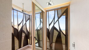 A modern interior with glass doors, a ceiling light fixture, and a view through the doors. - Villa Zaya - Designer Ocean-View Villa in Reserva Conchal (Santa Cruz)
