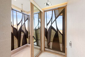 A modern interior with glass doors, a ceiling light fixture, and a view through the doors. - Villa Zaya - Designer Ocean-View Villa in Reserva Conchal (Santa Cruz)