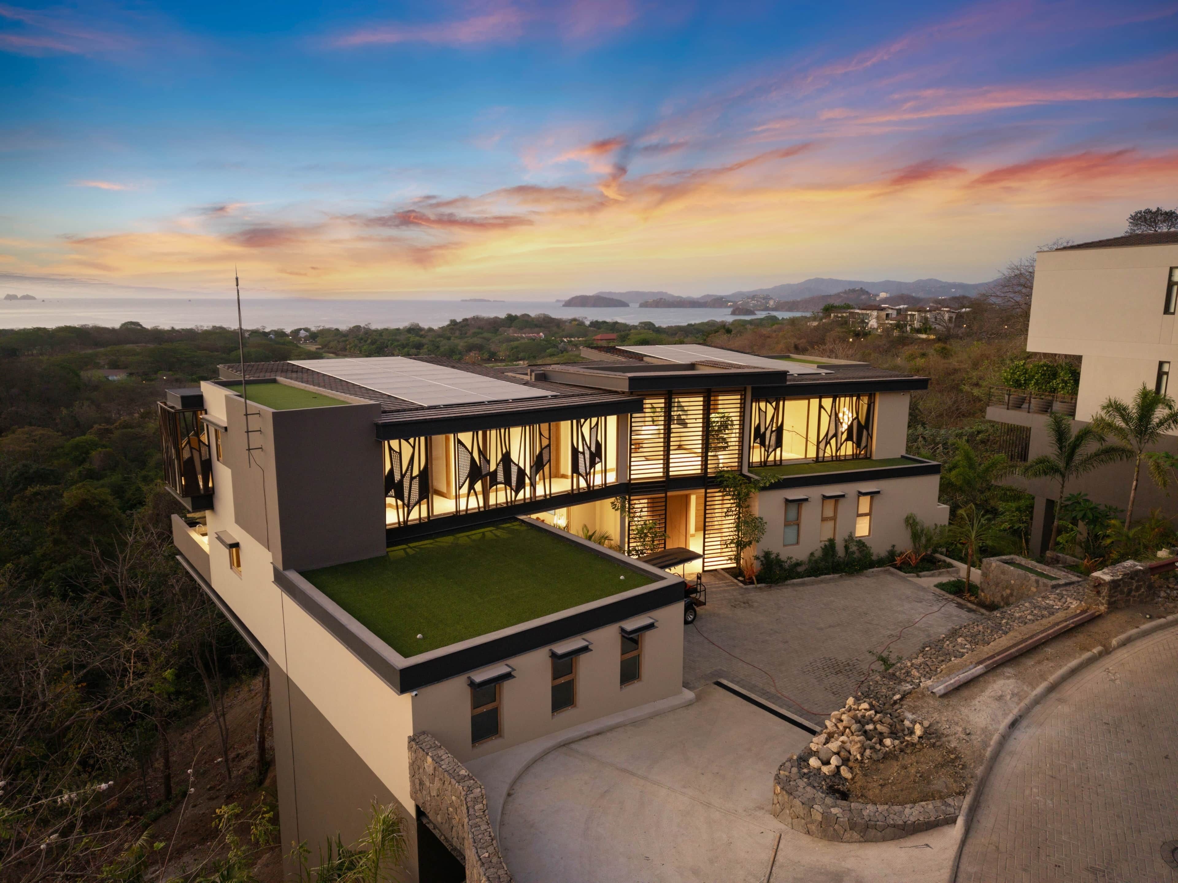 A modern house with a flat roof, large windows, and a well-maintained lawn.