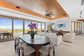Amplia sala de estar con mesa de comedor, sofás y ventanas grandes que ofrecen vistas del paisaje.
