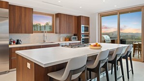 A modern kitchen with a large island, built-in appliances, and a view of the outdoors. - Villa Zaya - Designer Ocean-View Villa in Reserva Conchal (Santa Cruz)