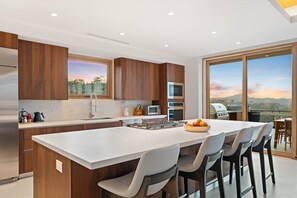 A modern kitchen with a large island, built-in appliances, and a view of the outdoors. - Villa Zaya - Designer Ocean-View Villa in Reserva Conchal (Santa Cruz)