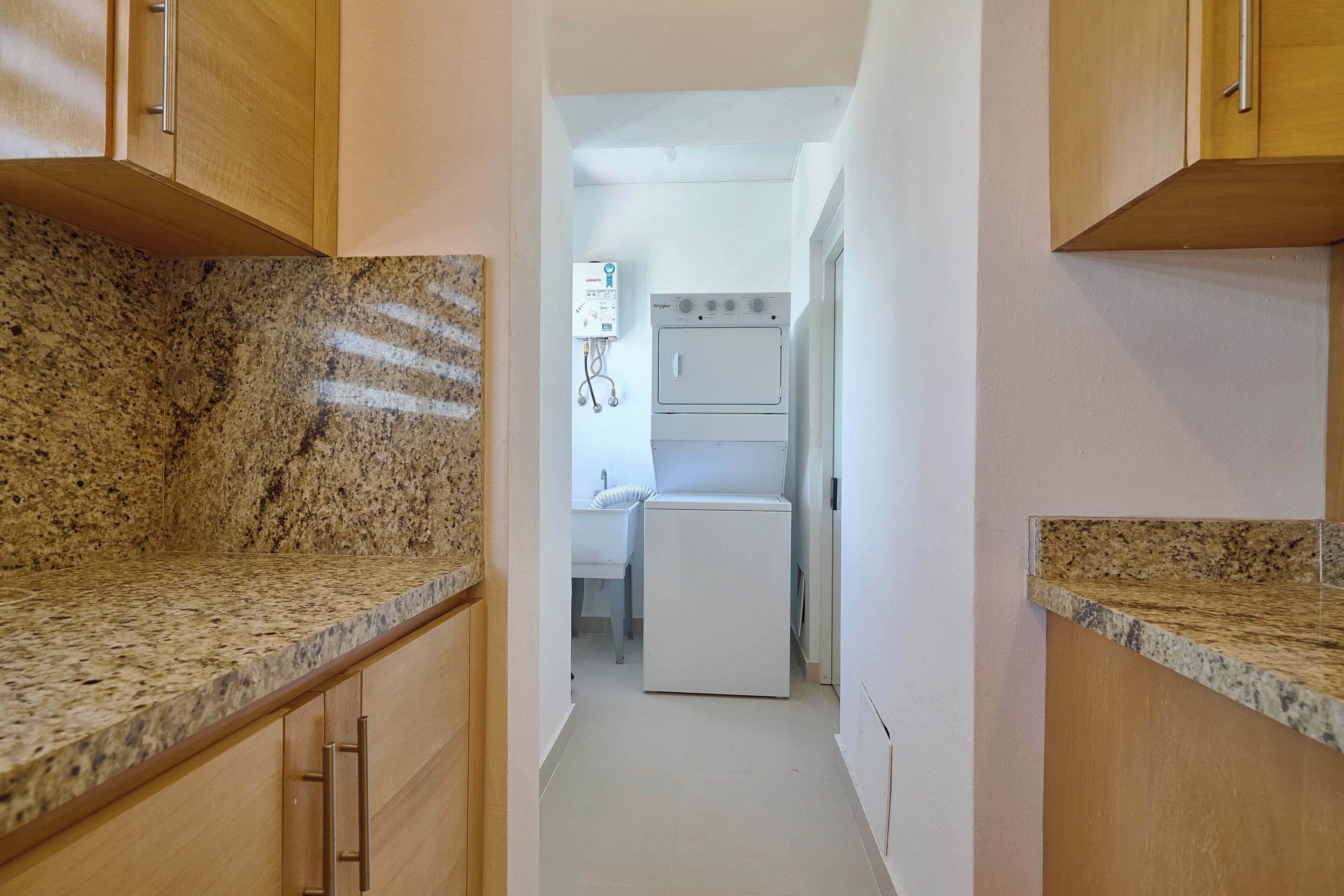 A narrow kitchen with granite countertops, wooden cabinets, and a built-in oven.