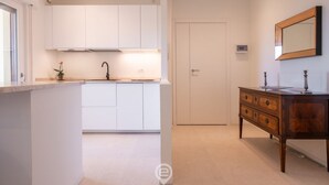 Et moderne køkken med hvide skabe, en central ø og et træmøbel med et spejl.