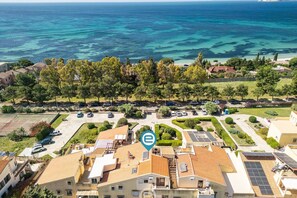 An aerial view of a residential area with houses, a parking lot, and a view of the sea. - Panoramic Seaview Apartment 2 (Quartu Sant'Elena)
