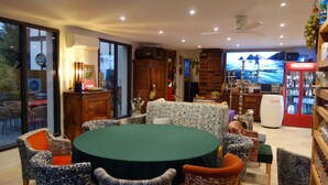 A spacious room with a large round table surrounded by patterned chairs, a television, and a minibar. - Hostelry private (Écully)