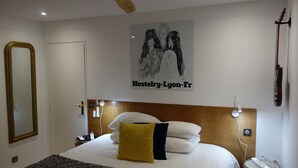 A hotel room with a bed, a headboard, a poster, a guitar, and a mirror. - Hostelry private (Écully)