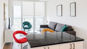 A modern kitchen with a black countertop, white cabinets, and a red bar stool.