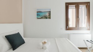 A bedroom with a bed, a pillow, a rolled towel, a window, and a wall-mounted picture. - House Adele - Dreaming Vacation (Villa San Pietro)
