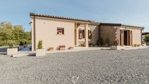 A two-story building with a beige facade, stone accents, and a gravel driveway. - House Adele - Dreaming Vacation (Villa San Pietro)