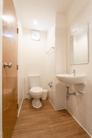 A small bathroom with a toilet, sink, and mirror. - Grandpa's Hostel Bangkok (Bangkok)