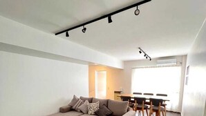 Un salon moderne comprenant un canapé d’angle, une table basse et un coin repas avec une table et des chaises.